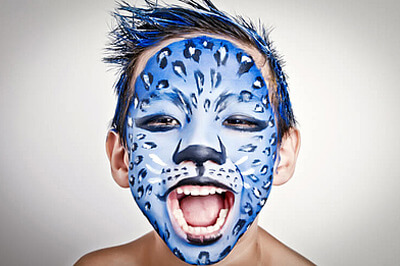 Kind mit blau, weiß und schwarz geschminktem Katzengesicht