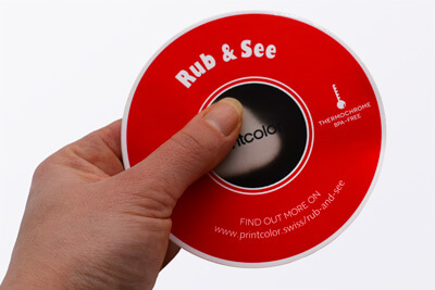 Eine Hand, die einen runden roten Aufkleber mit weißer Schrift festhält.