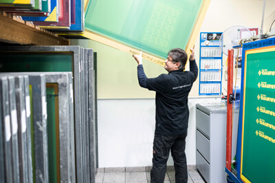 Mann der ein Drucksieb einsortiert