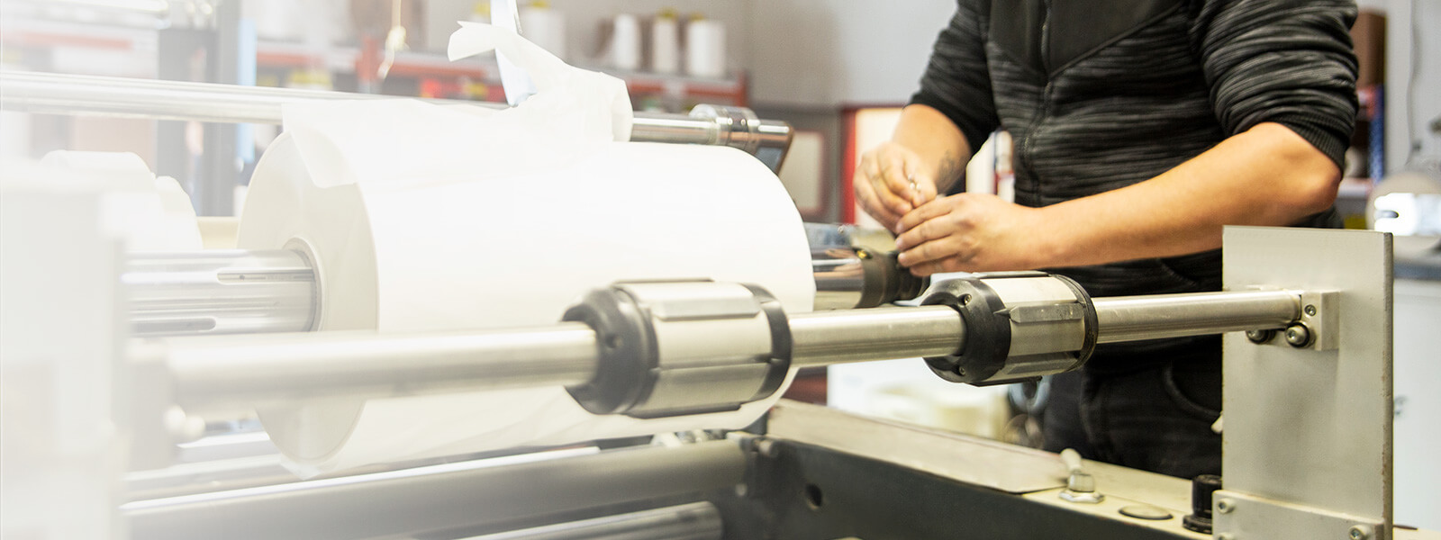 Mann steht an der Maschine für Folienkaschierung